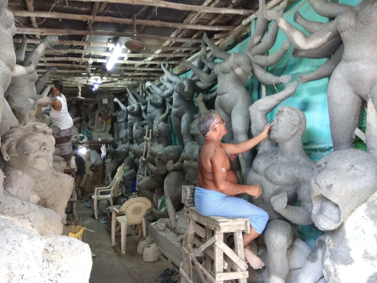 Artists sculpting clay idols in workshop.